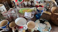 Full view of glassware, mugs, corn holders, small kitchen items on table