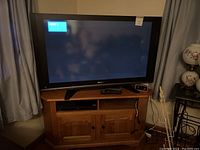 Panasonic 50 inch flat-screen TV on top of oak corner cabinet with DVD player on shelf