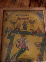 Full view of the vintage Poosh-M-Up Jr. 4-in-1 tabletop pinball game in wood frame with colorful playfield and glass top.