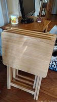 Set of 4 heavy wood folding TV tables stacked and folded, showing rectangular tops and foldable legs
