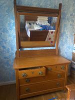 Front view of the wooden dresser with attached angled mirror and visible scratches on the surface