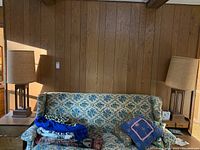Two matching floor lamps flanking a floral upholstered sofa against wood panel wall, showing overall size and appearance.