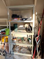 Front image showing full plastic storage shelf filled with various garden pots, household items, and plastic trays (contents not included). The shelf shows dirt and use.