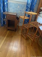 Full view of the wooden side table with drawer and cabinet door beside the separate wooden decorative stand with seven tiers.