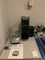 Overall view of the Keurig coffee maker and Oster Froth Max espresso frother on countertop with manuals laid out.