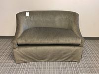 Front view of olive green upholstered loveseat with high rounded backrest and skirted bottom.