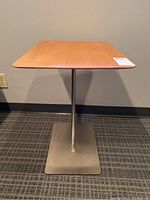 Front view of side table showing square wood top and metal pedestal with square base