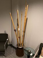 Front-side view of modern art display showing bamboo sticks in metal container and heavy metal base.