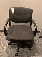 Front view of the United office chair showing black and grey tweed fabric, metal and plastic arms, and base with wheels.