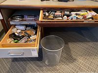 Photo showing open desk drawers with various office supplies and reader glasses.