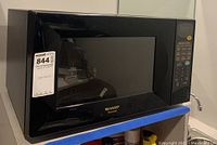 Front and side view of black Sharp Carousel microwave oven with door closed and visible control panel