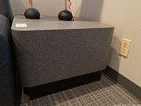 Side view of gray laminate side table showing textured surface and black base.