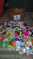 Photo showing over 100 colorful vintage buttons spread on floor with orange plastic container visible