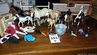 Photo showing all Breyer horses, rider figures, accessories, and the green horse trailer on wooden table.
