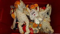 Red bin containing several Annalee Mobility dolls in holly pajamas, viewed from top