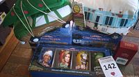Overview of the lot showing boxed pint glasses, plush RV and station wagon, and boxed mugs with Christmas tree and Hallmark ornament box visible