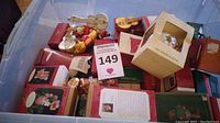 Photo showing numerous boxed Hallmark ornaments stacked together, some with original tags, including a yellow box for a glass ornament and assorted others.