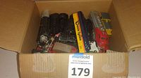 Several HO scale train engines and cars inside a cardboard box, viewed from above, showing condition and variety of pieces.