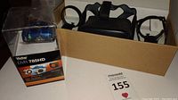 Vivitar DVR 785HD HD Action Camera in original retail packaging alongside Oculus Quest VR headset and controllers in a cardboard box.