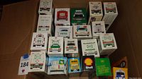Photo of 19 boxed toy trucks from Hess, Shell, BP, Ryder, and Sunoco brands arranged in a box.