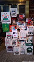 Photo of stacked boxed toy trucks from various brands including Hess, BP, Esso, and Exxon showing box art and size variety.