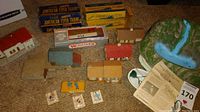 Photo showing a variety of model train accessories including multiple small model houses in various colors, boxes for Gilbert American Flyer trains, and a Williams train box.