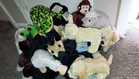 Image showing a collection of Webkinz plush toys including a frog, a turtle, a monkey, a porcupine, and various dogs piled together on carpeted floor.