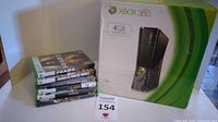 Xbox 360 console box with 4GB memory label alongside six Xbox 360 game cases stacked horizontally.