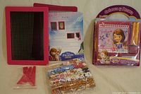 Pink pegboard for pixel art with bags of colored plastic pieces and Frozen-themed instruction sheet.