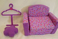 Photo showing the doll sofa bed in chair form, flower cushion, and hanger on flat surface.