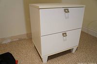Full view of the white 2-drawer cabinet standing on carpeted floor.