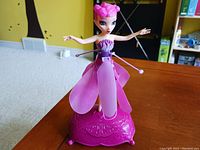 Pink flying fairy toy on magenta decorative base showing front detail