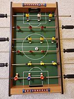 Top view showing complete foosball table with two teams, score counters, and ball in center.