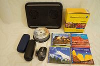 Photo showing Rosetta Stone French language software box, laptop fan pad, wireless mouse with USB receiver, two eyeglasses cases, a stack of DVD-R blank discs, and four touristic DVDs of Chilean locations.