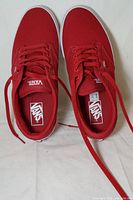 Top view of the pair of new red Vans sneakers showing the laces, Vans logo inside and on tongue.