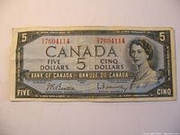 Front side of 1954 Canadian five dollar bill showing Queen Elizabeth II portrait, serial number 7694114, and signatures.