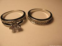 Photo of two silver tone rings with clear rhinestones on beige surface.