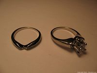 Two rings placed flat showing front and side profiles with clear stones and silver-tone finish.