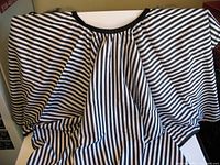 Unfolded black and white horizontally striped cape with gathered neckline and black trim
