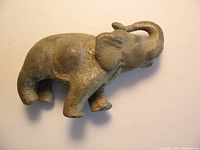 Full view of antique lead toy elephant showing body shape, texture and raised trunk