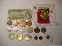 Overview of all tokens, medals, coins and currency presented together, including the Canadian dollar bill and red pouch