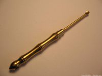 Brass combination ear wax spoon with pointed end and hidden toothpick unscrewing mechanism.