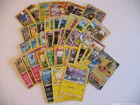 Spread out and stacked view of approx 49 used Pokemon trading cards including popular characters and Trainer cards.