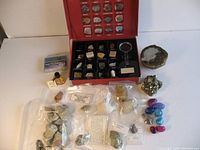 Full lot overview showing boxed Scholastic rock and mineral kit, bottle of gold flakes, meteorites, fossils, and mineral samples arranged on white surface.