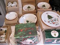 Full view of boxed and unpacked porcelain items showing cups, plates, bowls, and boxed teapot and candle holders with Christmas tree decoration