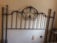Full view of queen size bed frame's headboard showing ornate twisted metal rods and chain link detailing in pewter color.