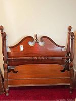 Full view of the assembled wooden twin bed frame showing headboard and footboard with carved posts and decorative features.