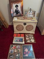 White embroidered storage chest with latch, six picture frames arranged on top and front