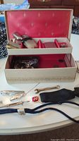 Overall view of the box with men's accessories including cufflinks, manual razor, lighters, bolo tie and tie clips arranged on a table.