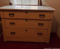 Front view of vintage dresser showing three drawers with metal handles and worn painted finish.